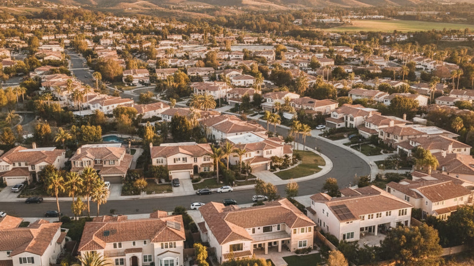 Aerial view of a San Diego County residential neighborhood with stucco homes and tile roofs at golden hour